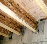 Wooden I-beams connected to the basement wall.